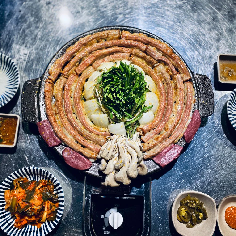 黑色鑄鐵烤盤上盤成漩渦狀的牛小腸與中央的韭菜