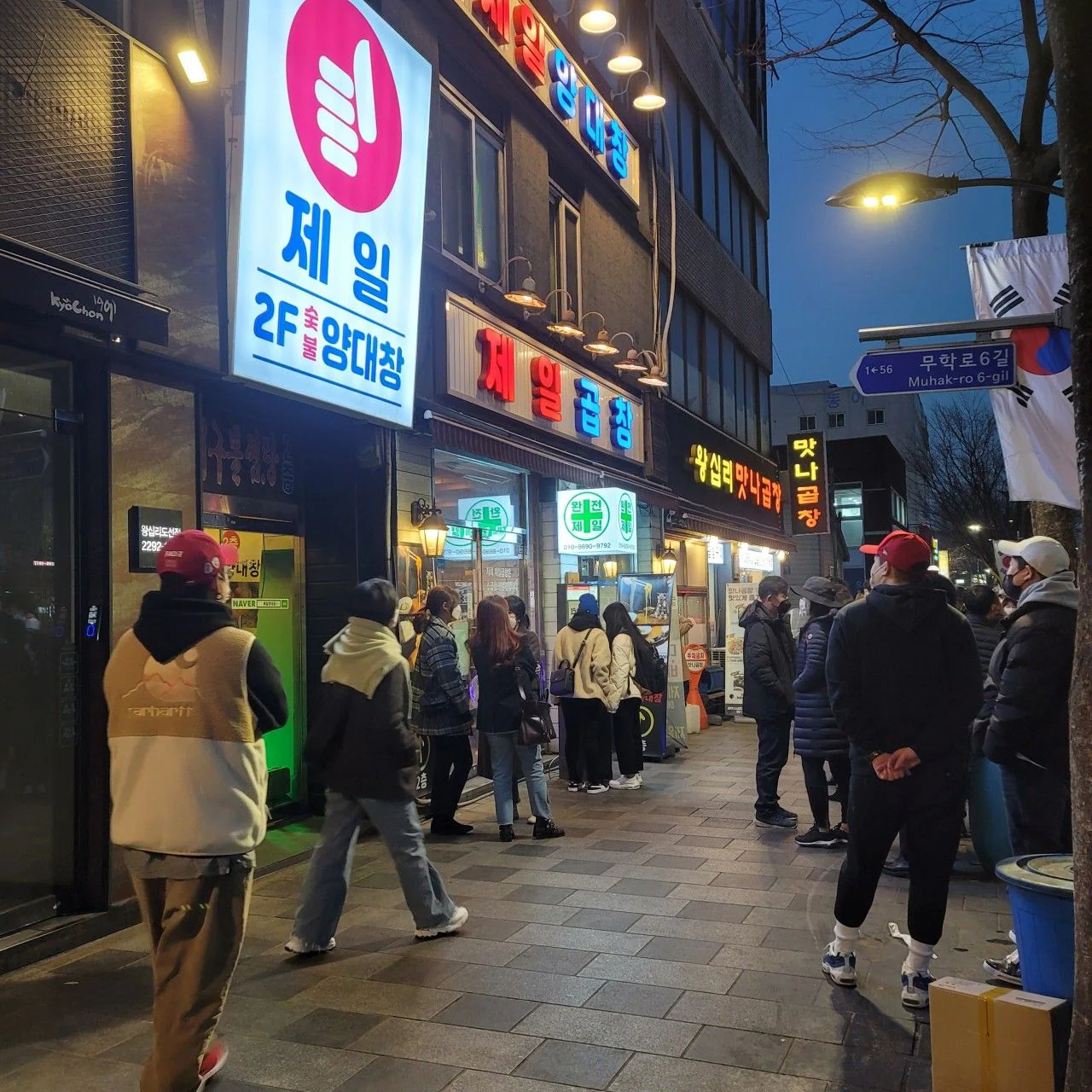 傍晚街道上的「제일곱창」招牌與店門口的客人